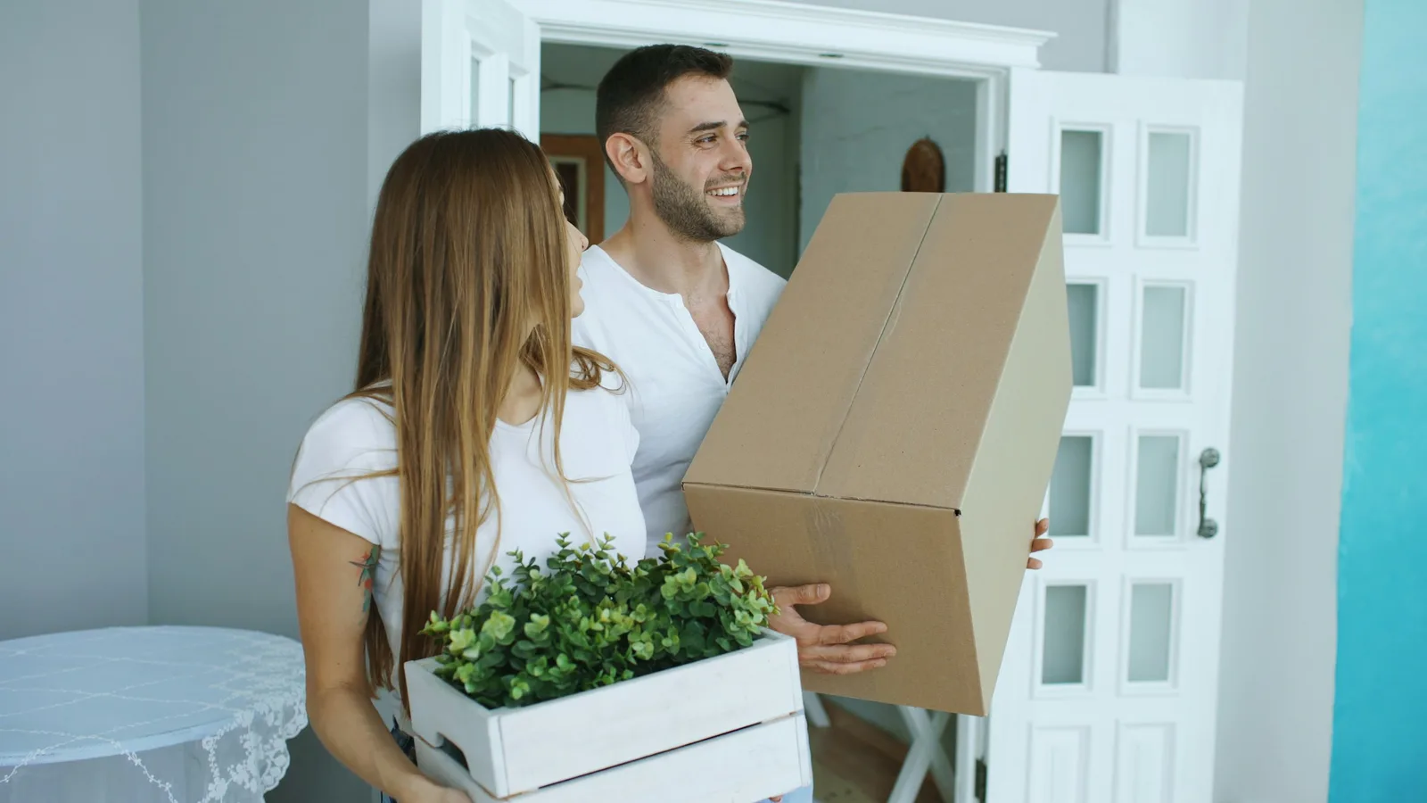 A couple carrying boxes into a new home, the end point of a Paraguay relocation checklist